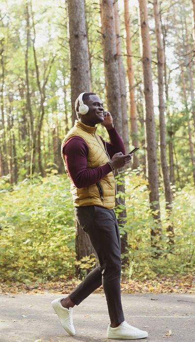 African american man listens music in spring park copy space and place for advertising. Gadget, app and streaming service concept