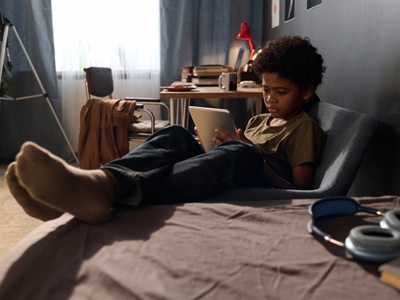Black Boy Using Tablet on Bed